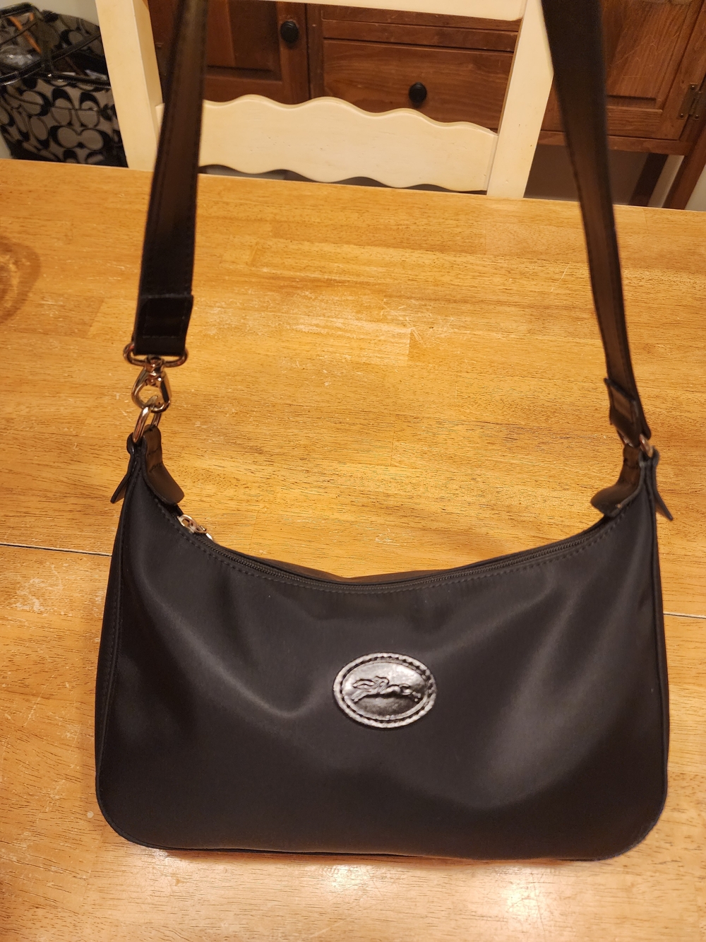 Longchamp black nylon hobo shoulder bag featuring a curved top-zip design